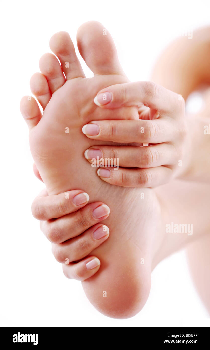 Jeune femme massages son pied. Sur un fond blanc. Banque D'Images