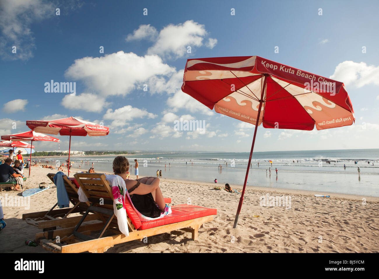 L'INDONÉSIE, Bali, Kuta, plage, femme assise sur une chaise longue à l'ombre de garder propre parasol de plage de Kuta Banque D'Images