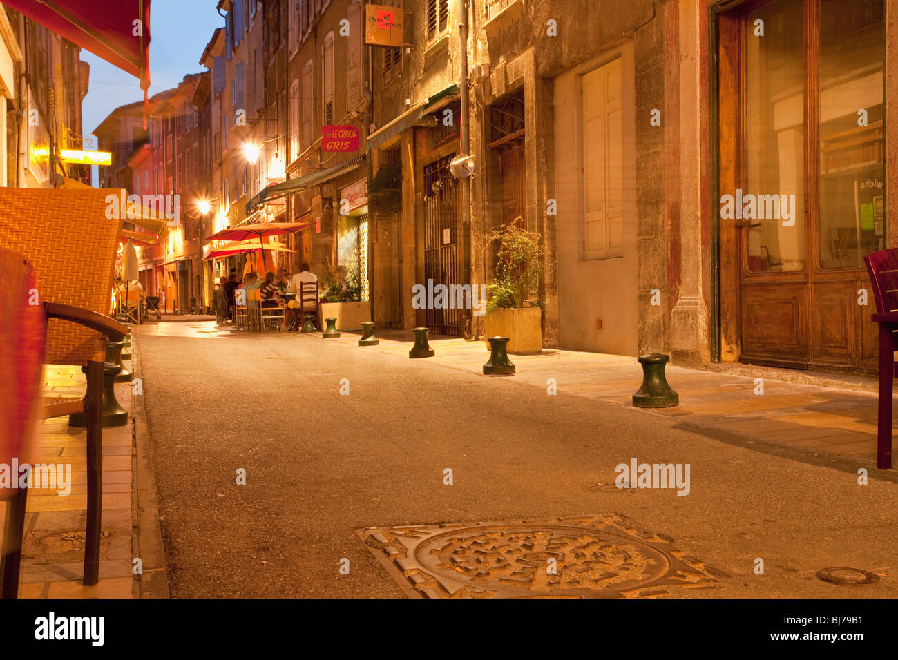 Ambiance crépusculaire dans une charmante allée de Sisteron avec des cafés de rue confortables Banque D'Images