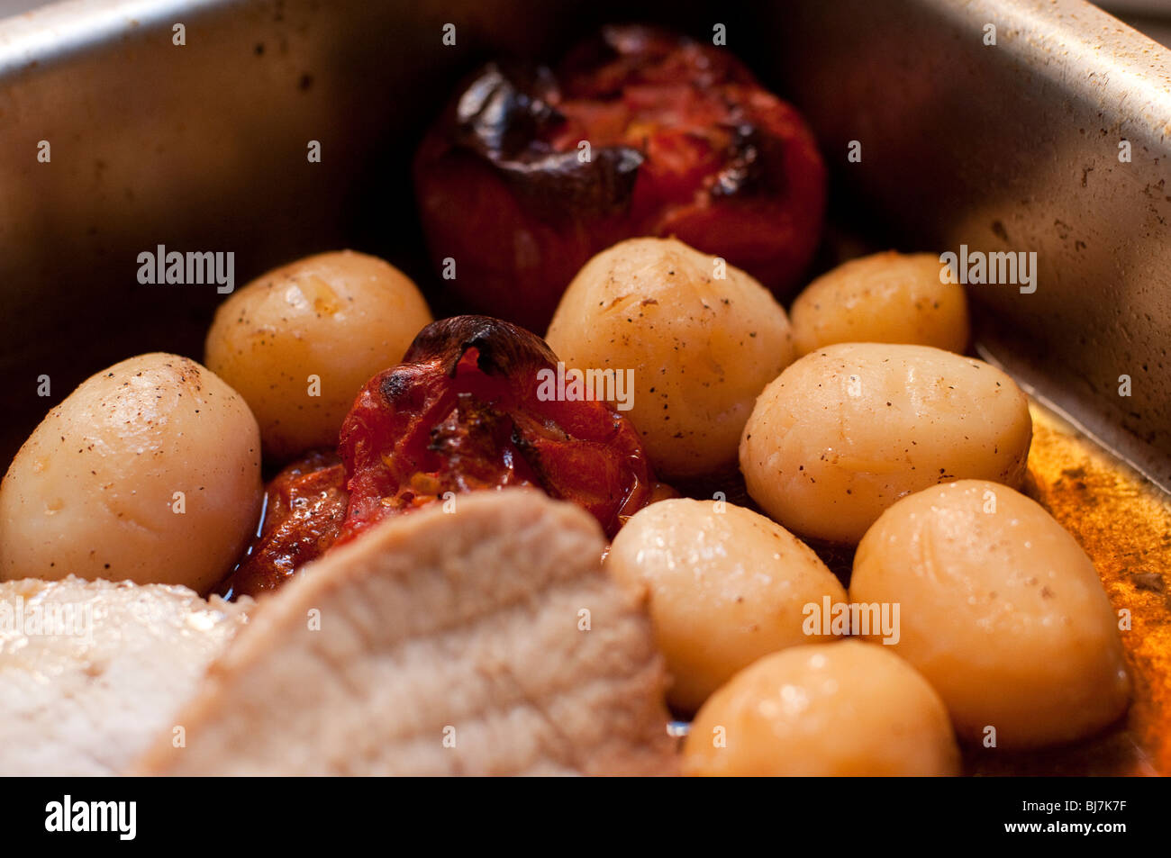 Petit tour des pommes de terre et les tomates avec des tranches de porc cuit au four Banque D'Images