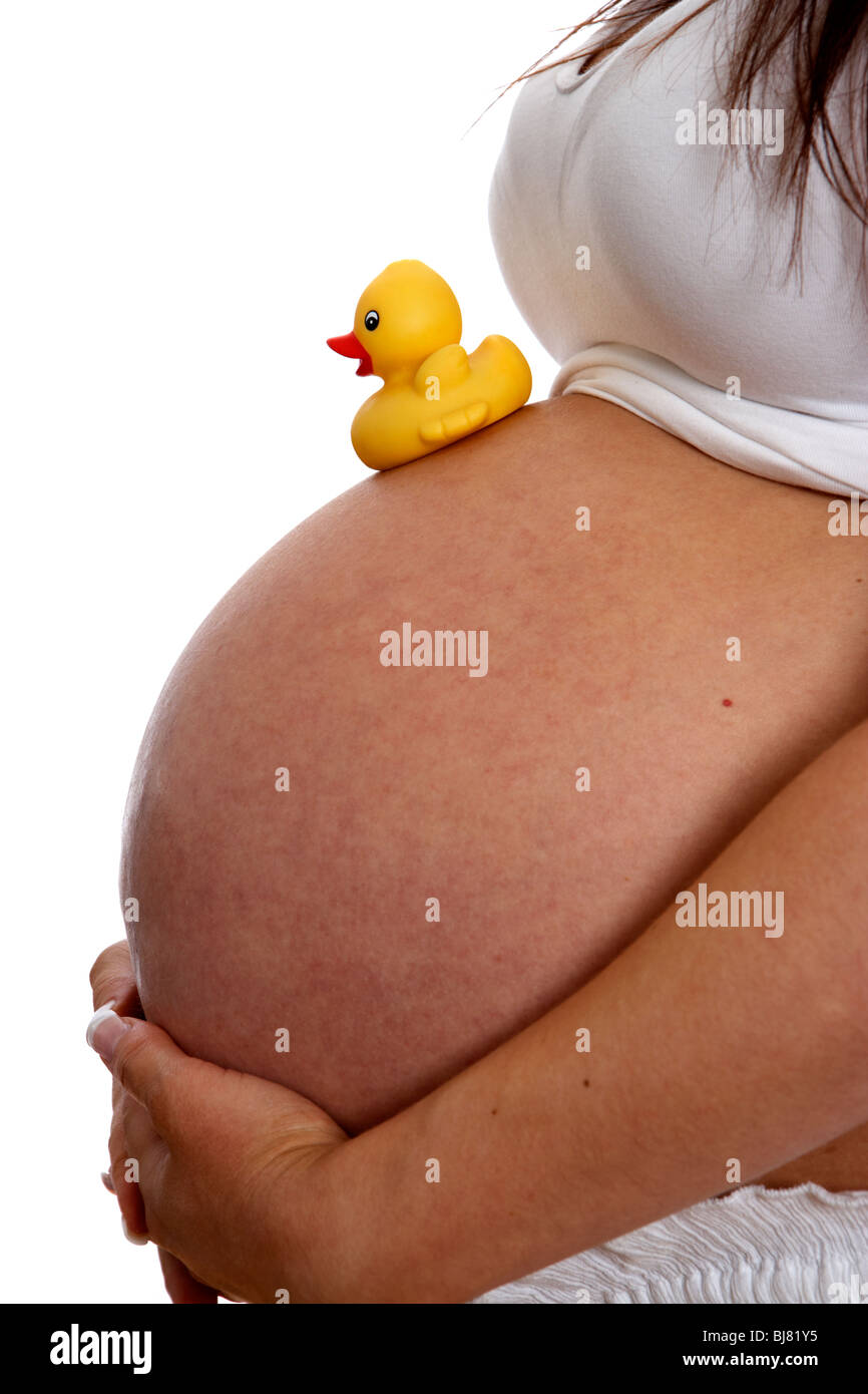8 mois femme enceinte de 30 ans avec de petits canards en plastique jaune childs sur baby bump Banque D'Images