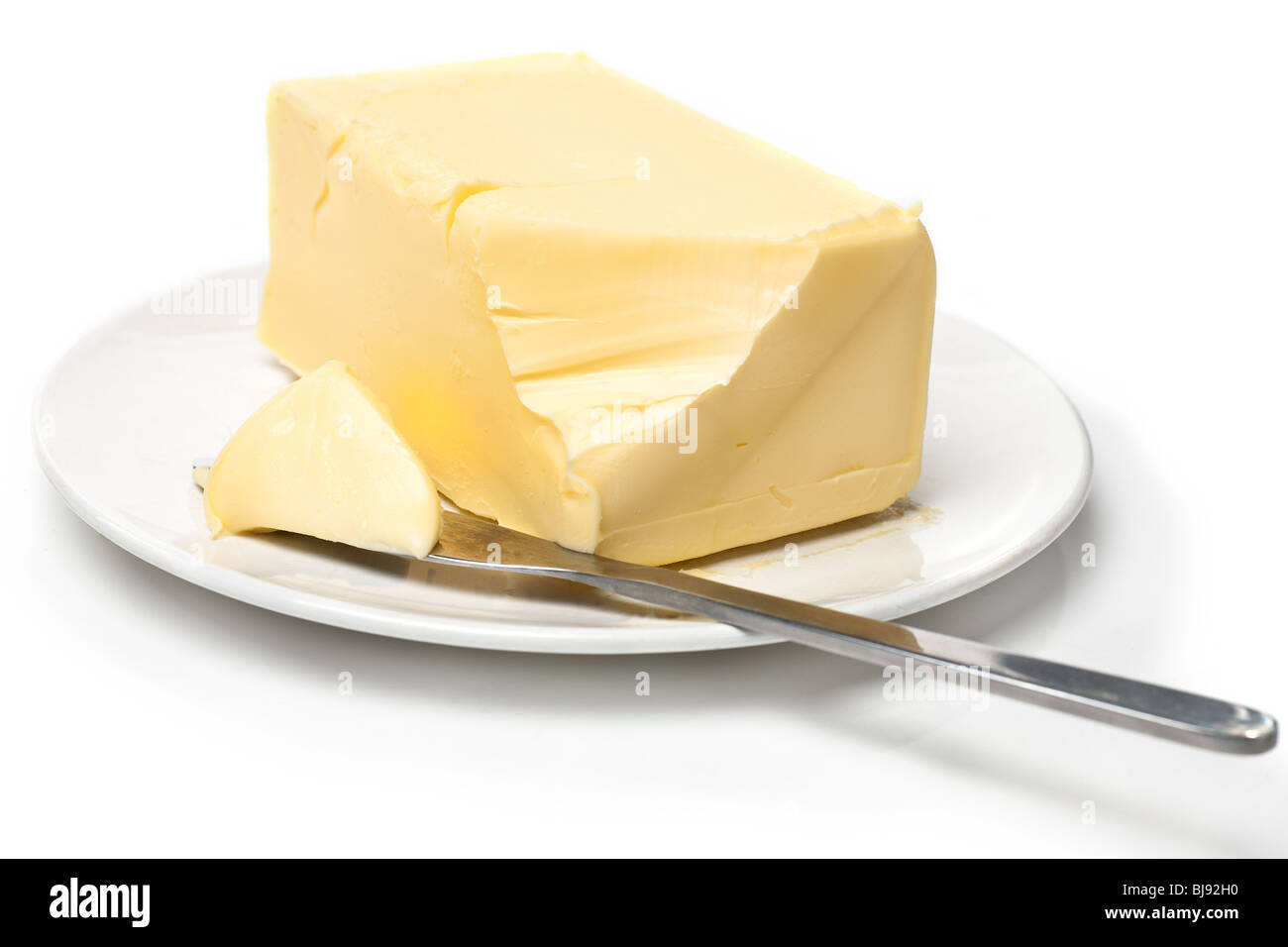 Morceau de beurre sur la plaque blanche avec un couteau. Fond blanc et l'accent peu profondes. Banque D'Images