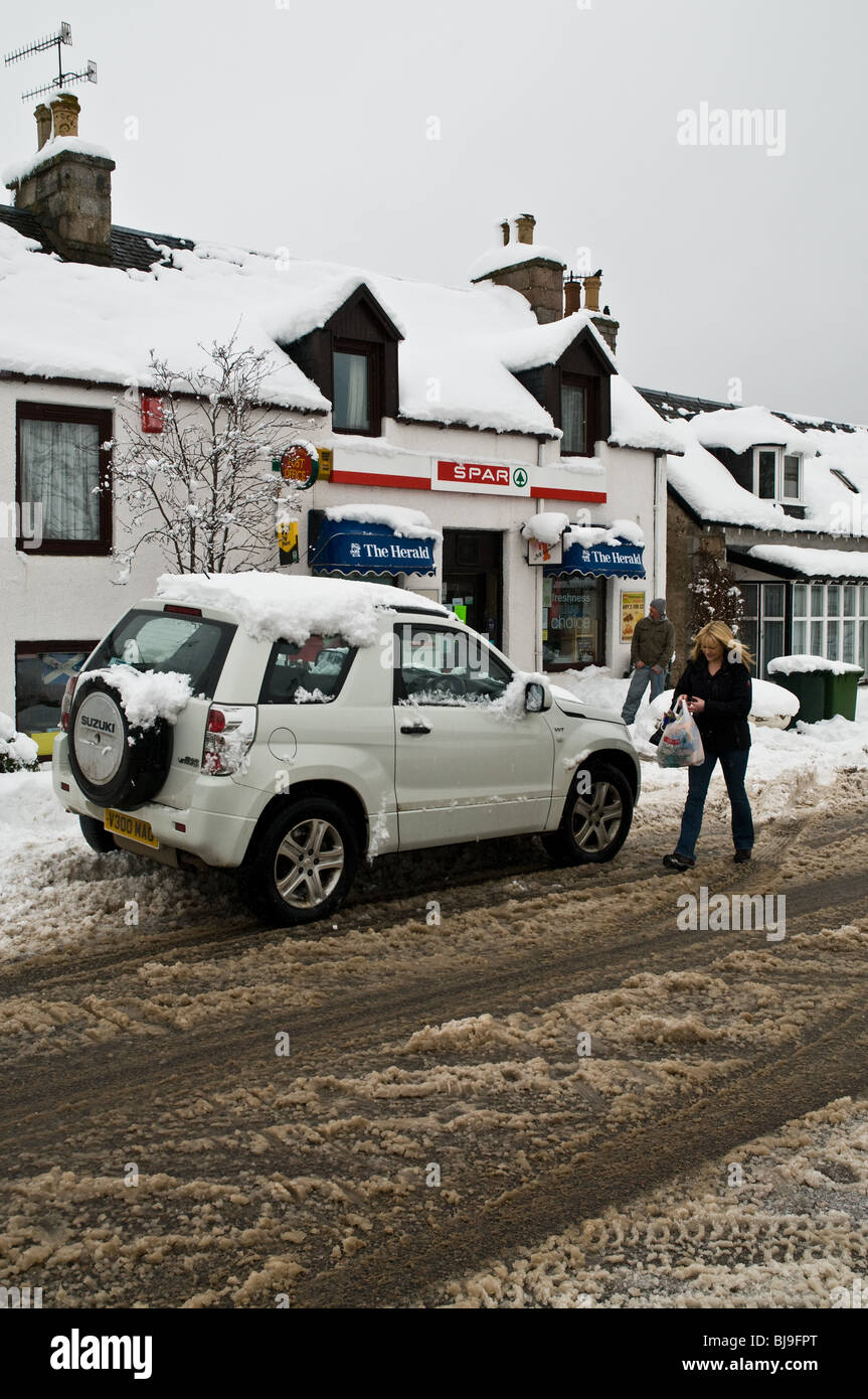 dh Scottish rural village boutique CARRBRIDGE INVERNESSSHIRE femme shopper 4x4 Voiture hors de la neige météo Ecosse royaume-Uni Banque D'Images