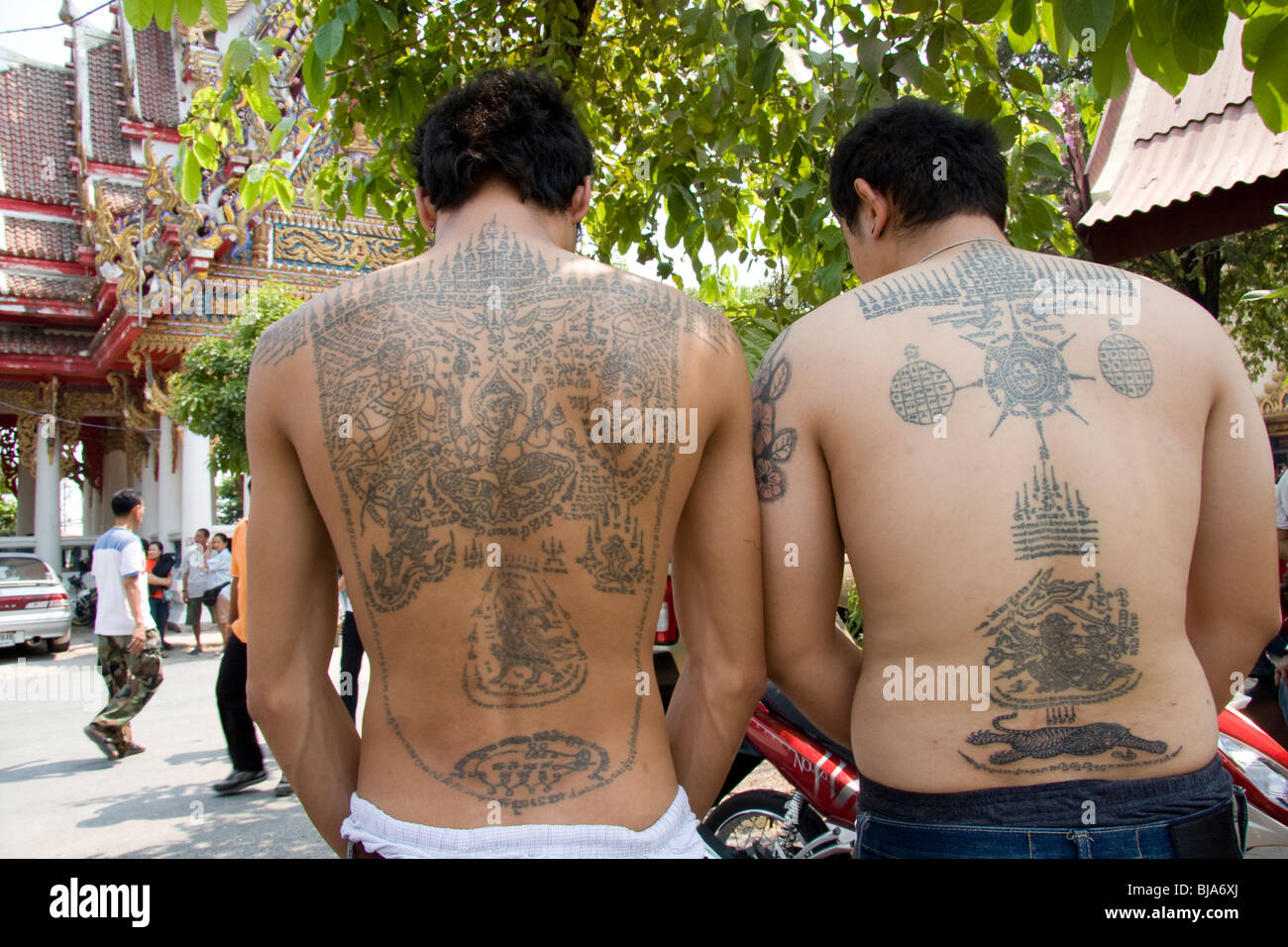 Les hommes exhibant tatouages dos au Wat Bang Phra temple en Thaïlande, où les moines dévots leur tatouage avec des prières. Banque D'Images