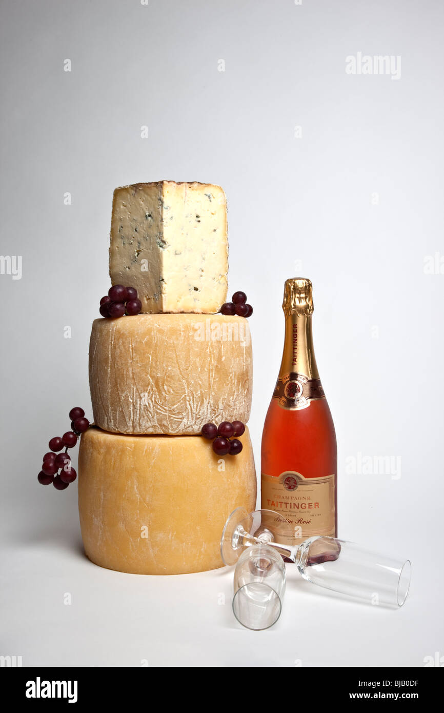 Une célébration de la tour ronde de fromages entiers avec un grand support de fromage bleu avec une bouteille de champagne et deux verres rose Banque D'Images