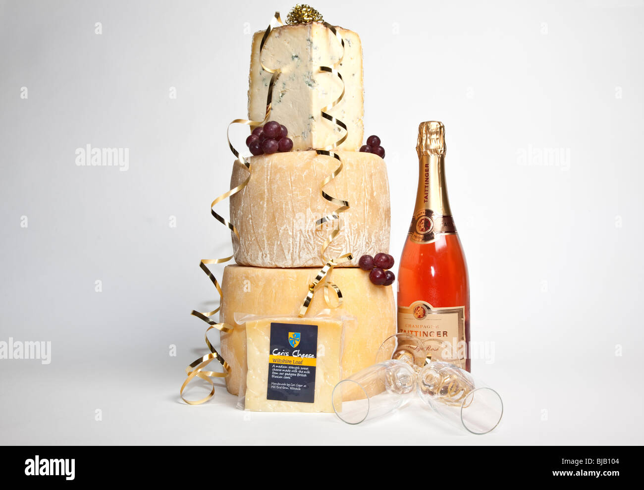 Une célébration de la tour ronde de fromages entiers avec un grand support de fromage bleu avec une bouteille de champagne et deux verres rose Banque D'Images