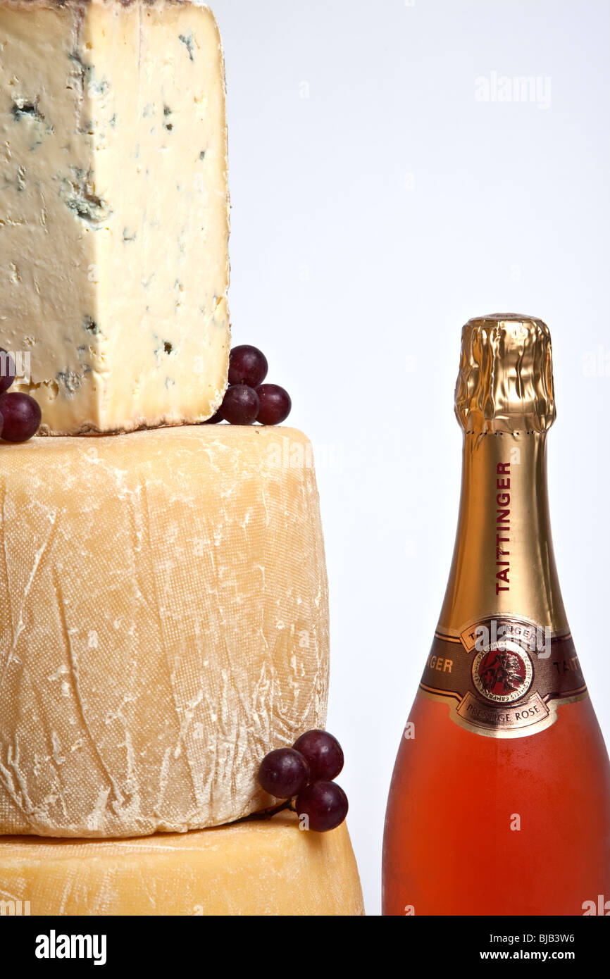 Une célébration de la tour ronde de fromages entiers avec un grand support de fromage bleu avec une bouteille de champagne rose Banque D'Images