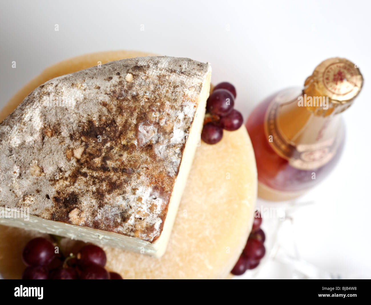 Une célébration de la tour ronde de fromages entiers avec un grand support de fromage bleu avec une bouteille de champagne rose Banque D'Images