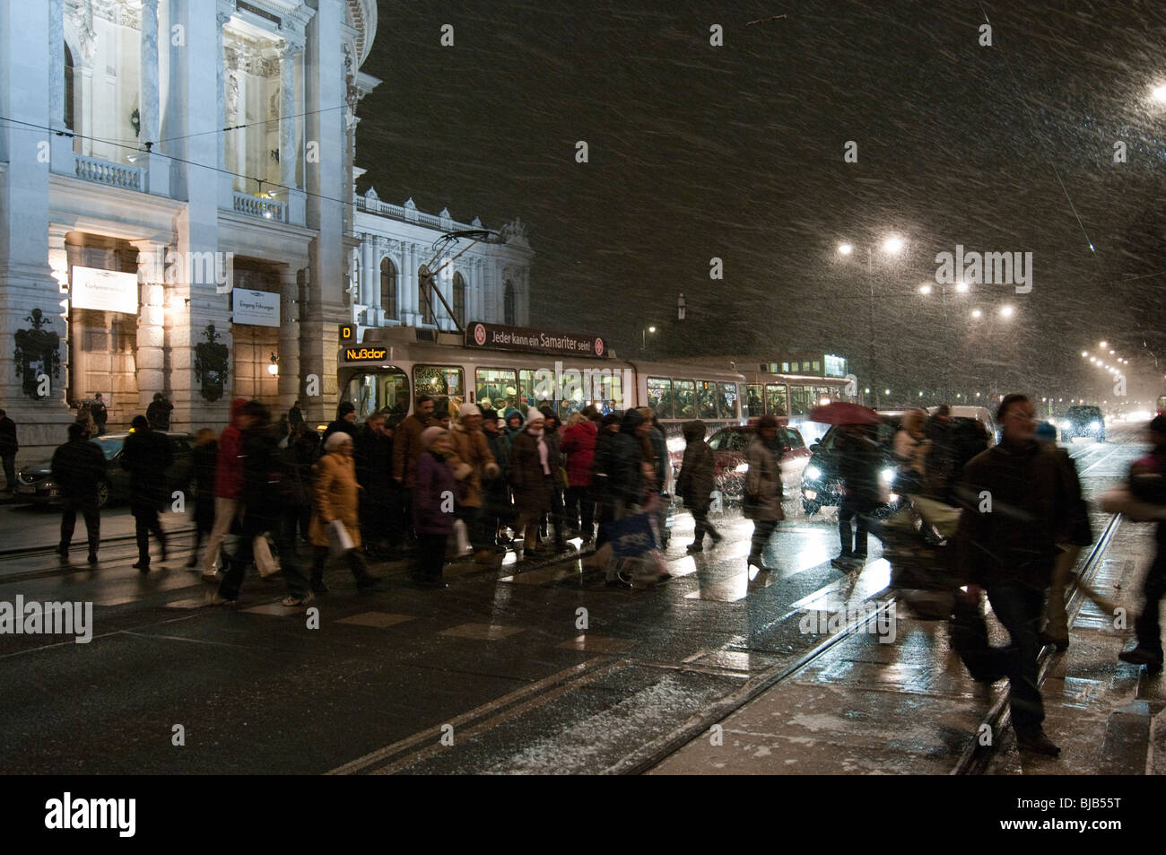 Shoppers traverser la route en face du tram lors d'une tempête de neige à Vienne, Autriche Banque D'Images