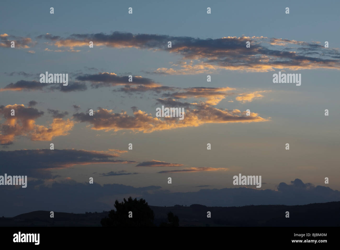 L'assombrissement du ciel avec nuages épars mis en lumière par le soleil couchant. Midlands, Kwazulu Natal, Afrique du Sud. Banque D'Images