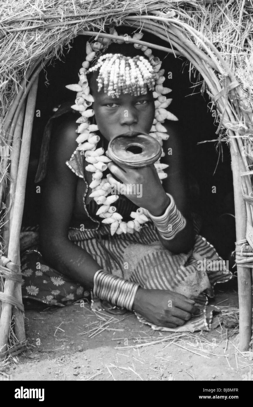 Fille de la tribu Mursi avec plaque de lèvre est assis à l'entrée de sa hutte, vallée de l'Omo, Ethiopie Banque D'Images
