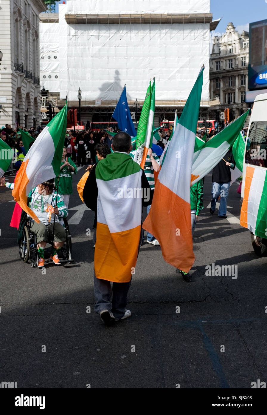 Les personnes portant le drapeau tricolore irlandais pendant la St Patricks Day Parade à Londres. Banque D'Images