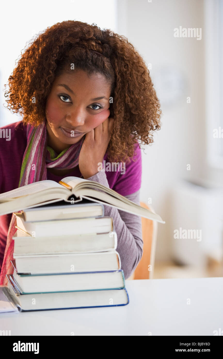 Mixed Race woman looking at pile de livres Banque D'Images