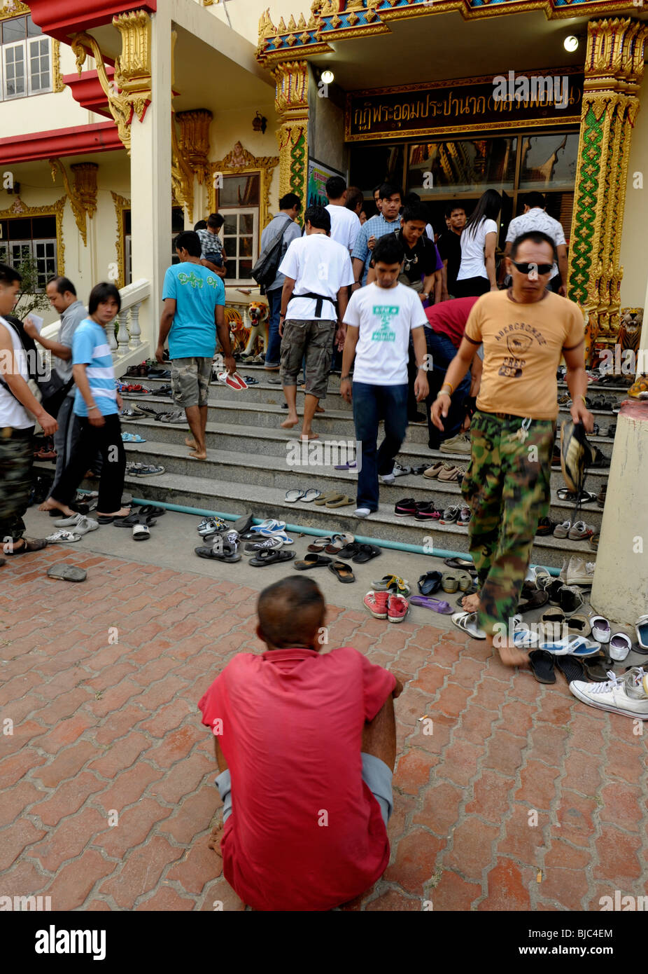 Mendiant en gardant un œil sur les gens de la chaussure petit changement , wat Bang Phra Nakhon , chiasi, Thaïlande Banque D'Images