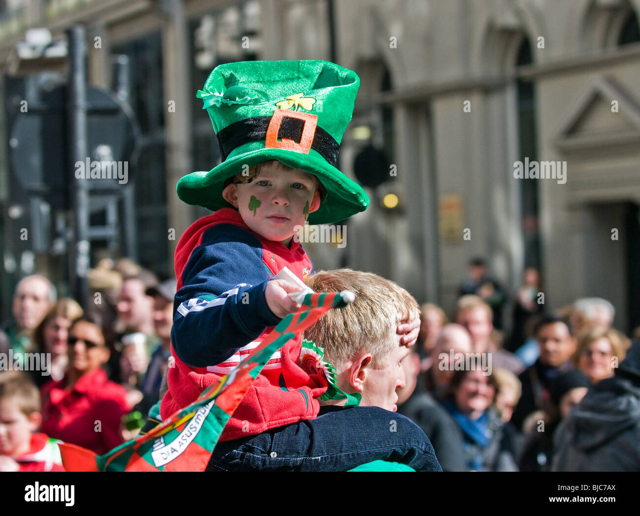 Un enfant assis sur les épaules de son père pendant la St Patricks Day Parade à Londres. Banque D'Images