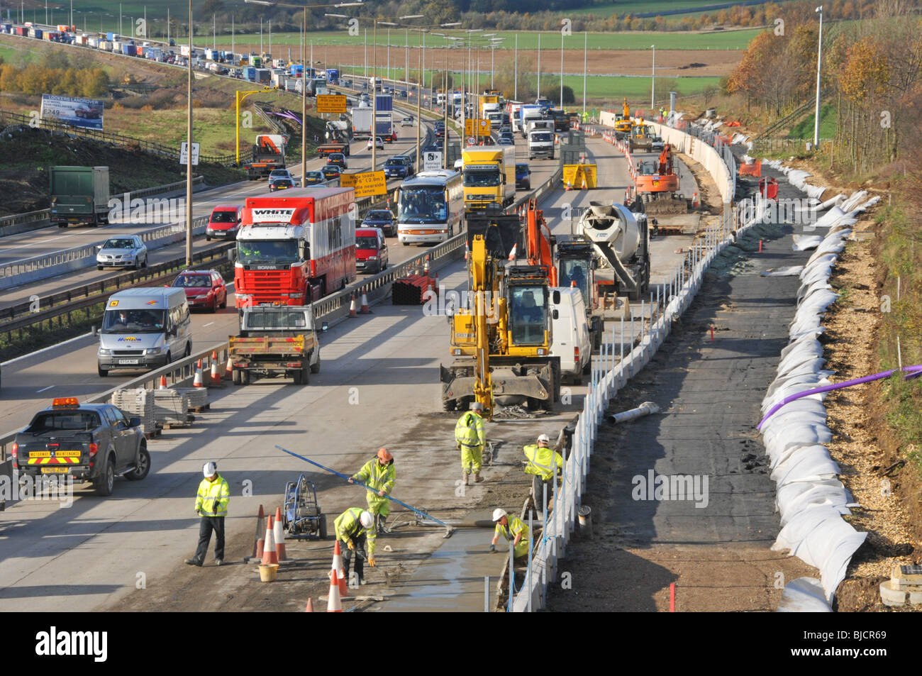 Autoroute M25 embouteillage de la circulation à contre-courant de l'autoroute retour parmi les ouvriers de la construction élargissant la route à quatre voies dans le paysage rural de l'Essex Angleterre Banque D'Images