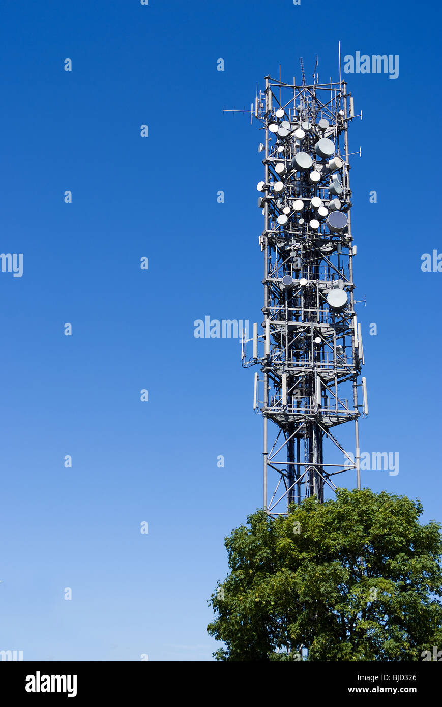 Un grand mât de communication avec de nombreux plats et aériens Banque D'Images