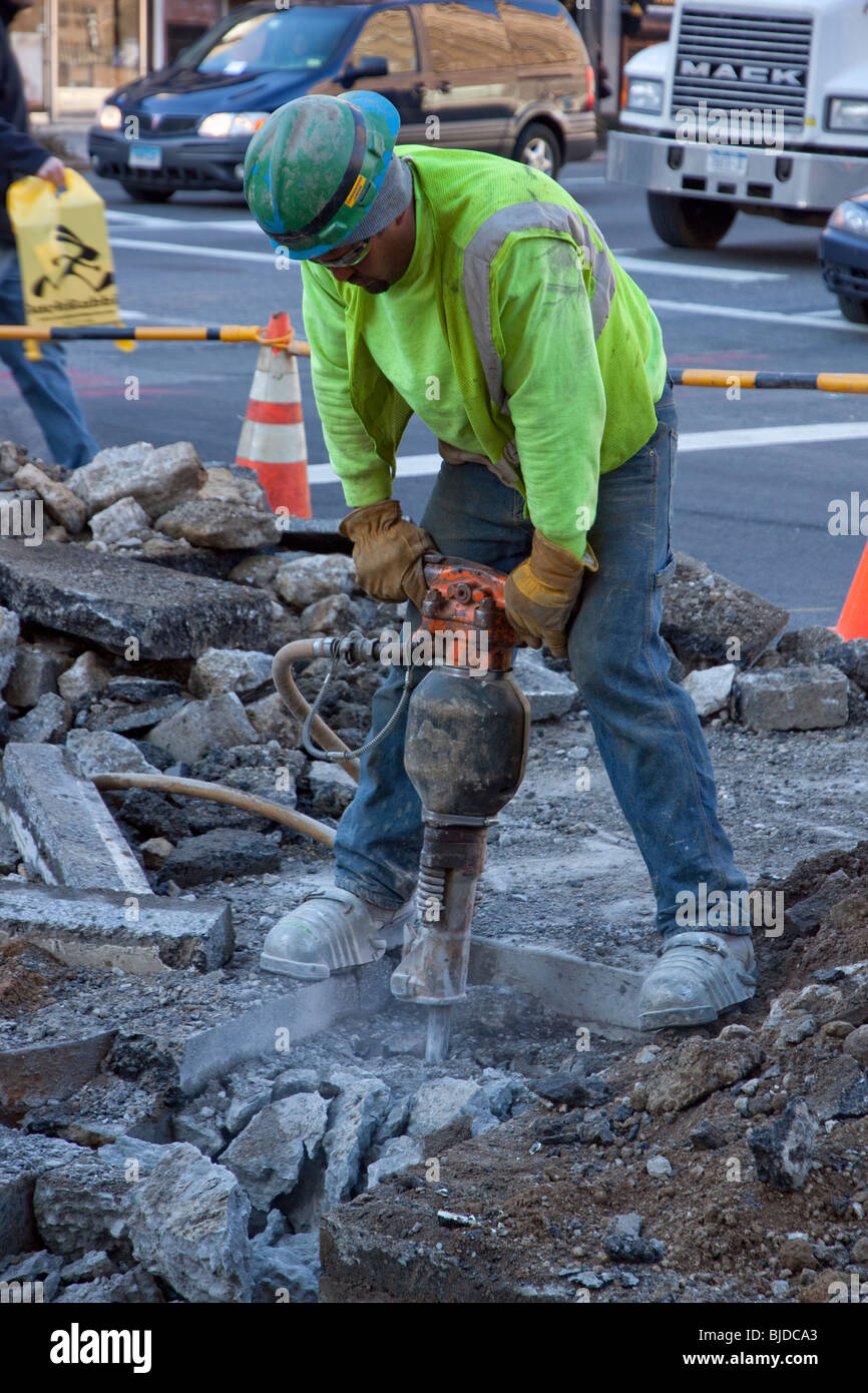 Mâle adulte travailleur d'entretien des routes à l'aide d'un marteau-piqueur. Banque D'Images