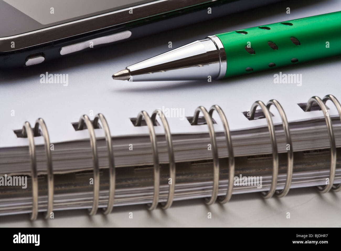 Gros plan extrême d'un stylo à bille, carnet à spirales et cell phone Banque D'Images