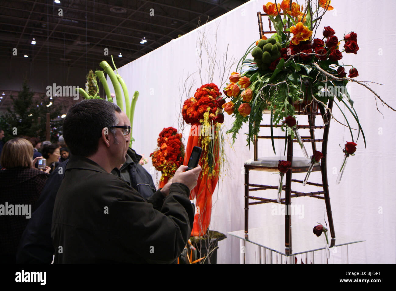 Homme à prendre des photos d'un arrangement floral à l'aide de son appareil photo numérique de l'iPhone d'Apple Banque D'Images
