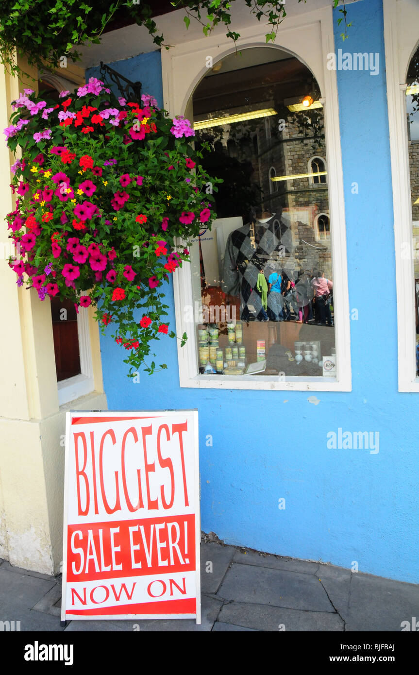 Une vente signer avec un pot de fleurs colorées à l'extérieur d'un magasin de vêtements au Royaume-Uni Banque D'Images