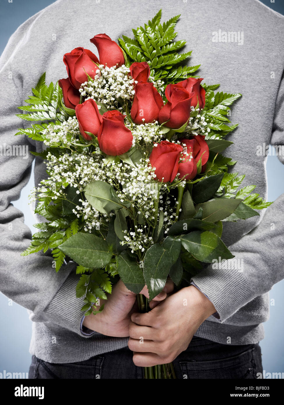 L'homme avec des fleurs derrière son dos Banque D'Images