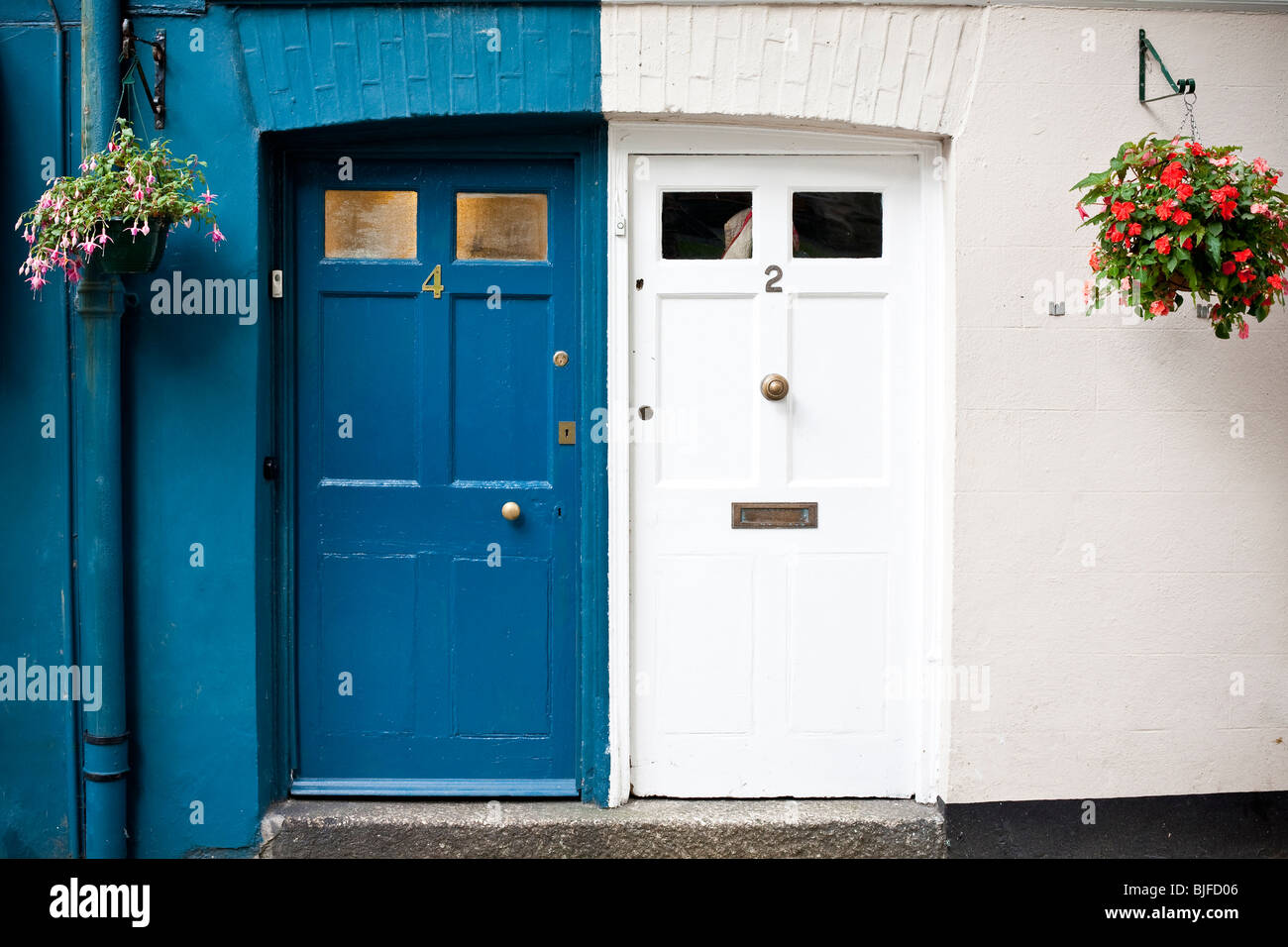 Chalet bleu et blanc, les portes d'entrée avec des paniers suspendus, Cornwall, Angleterre. Banque D'Images