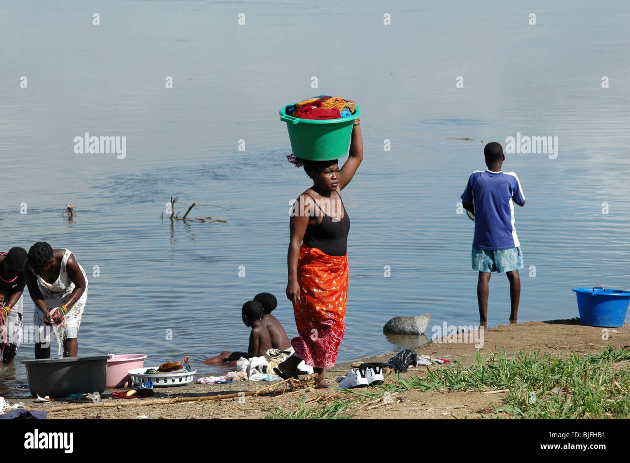 Les femmes laver et nettoyer les casseroles et poêles dans le puissant fleuve Zambèze à l'AICA traversée en ferry. Caia, Zambèze, au Mozambique, l'Afrique Banque D'Images
