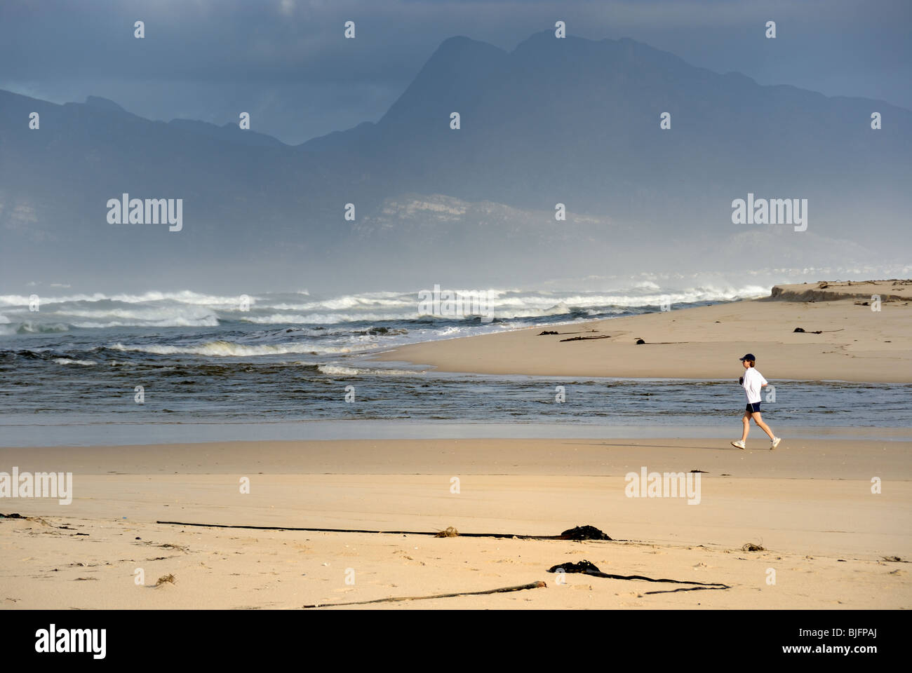 Femme en marche le matin sur la plage, à l'estuaire de la mer / lac à Hermanus, South Western Cape, Afrique du Sud Banque D'Images