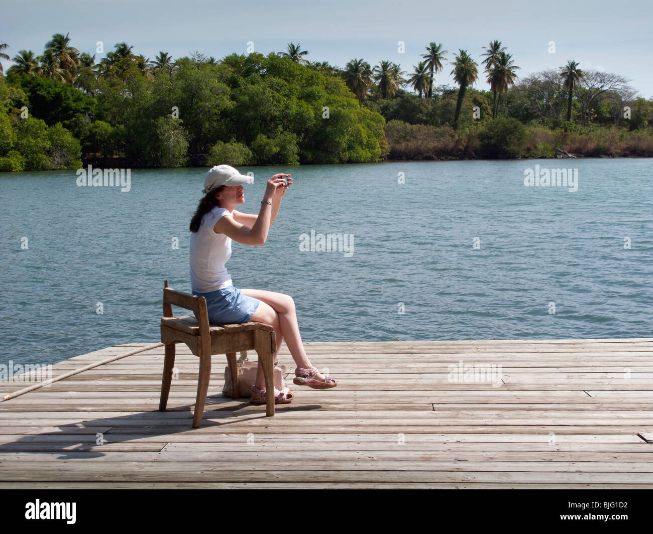 Girl utilise de vieux assise en bois sur une jetée à l'appui tandis que la composition d'une photographie de la côte des Caraïbes avec palmier toile Banque D'Images