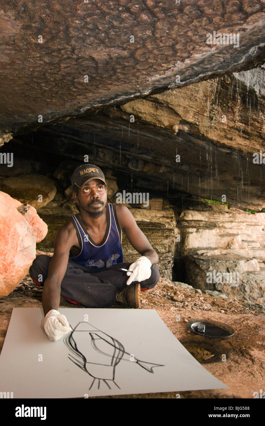 L'artiste autochtone Terence Nabegeyo une lithographie gravure dans une grotte sous la pluie sur la terre d'Arnhem orientale Injalak Hill Banque D'Images