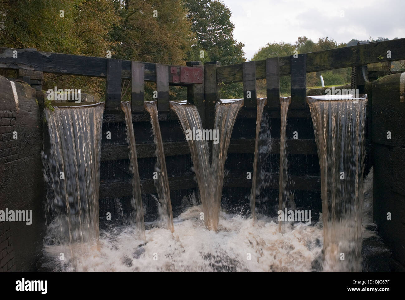 Cascade à travers 'Dépassement' portes d'une serrure sur le canal de Rochdale, Yorkshire, UK. Banque D'Images