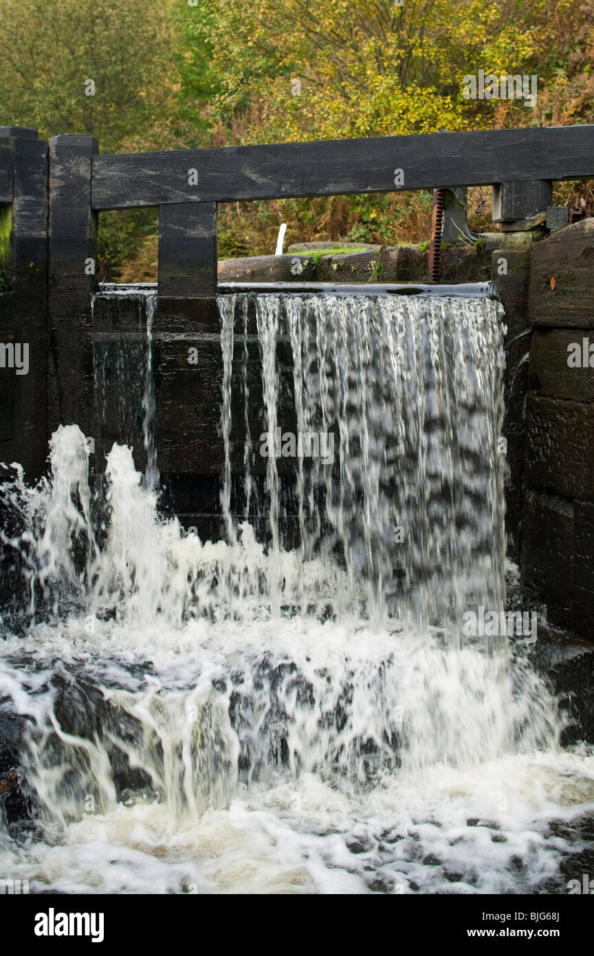 Cascade à travers 'Dépassement' portes d'une serrure sur le canal de Rochdale, Yorkshire, UK. Banque D'Images