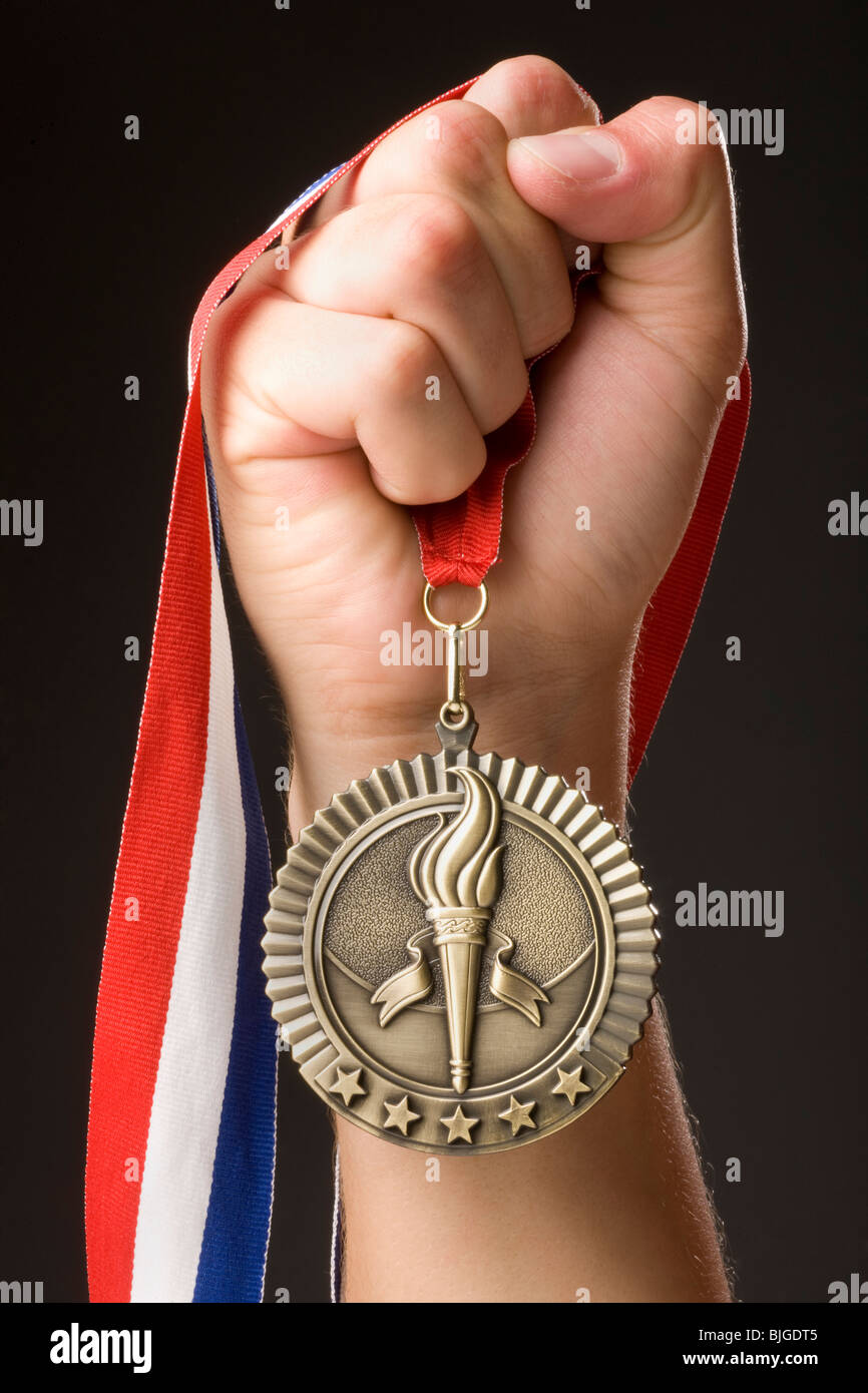 Main tenant une médaille d'or Banque D'Images