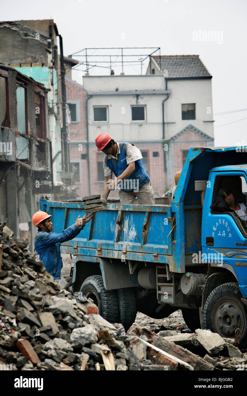 Les travailleurs de la construction faire place à de nouveaux immeubles de grande hauteur, qui sont la prise en charge de l'ancien Shanghai zones résidentielles. Banque D'Images