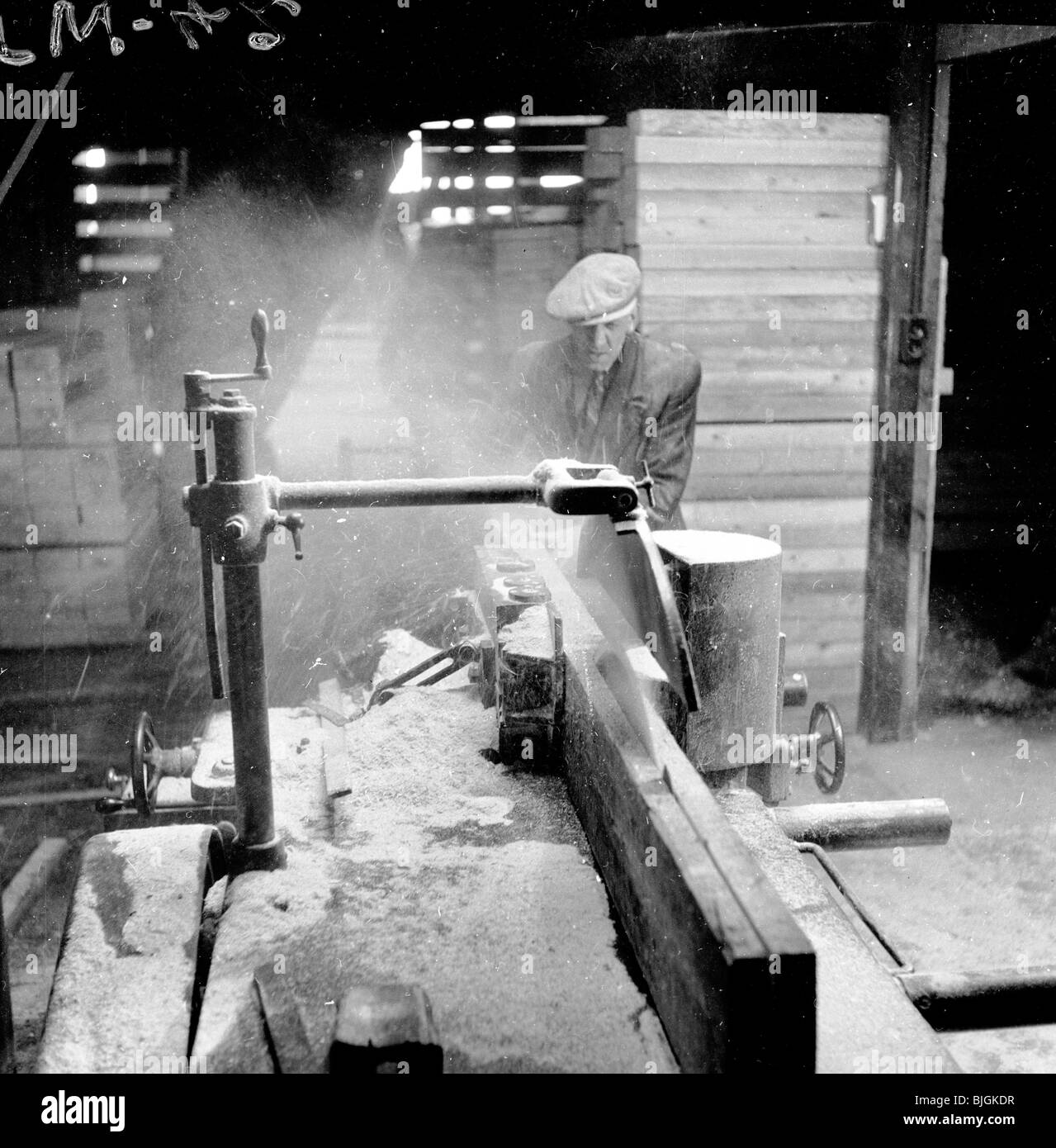 Angleterre, années 1950. Male construction worker wearing cap, et l'enveloppe, à l'exploitation d'une machine à couper du bois. Banque D'Images