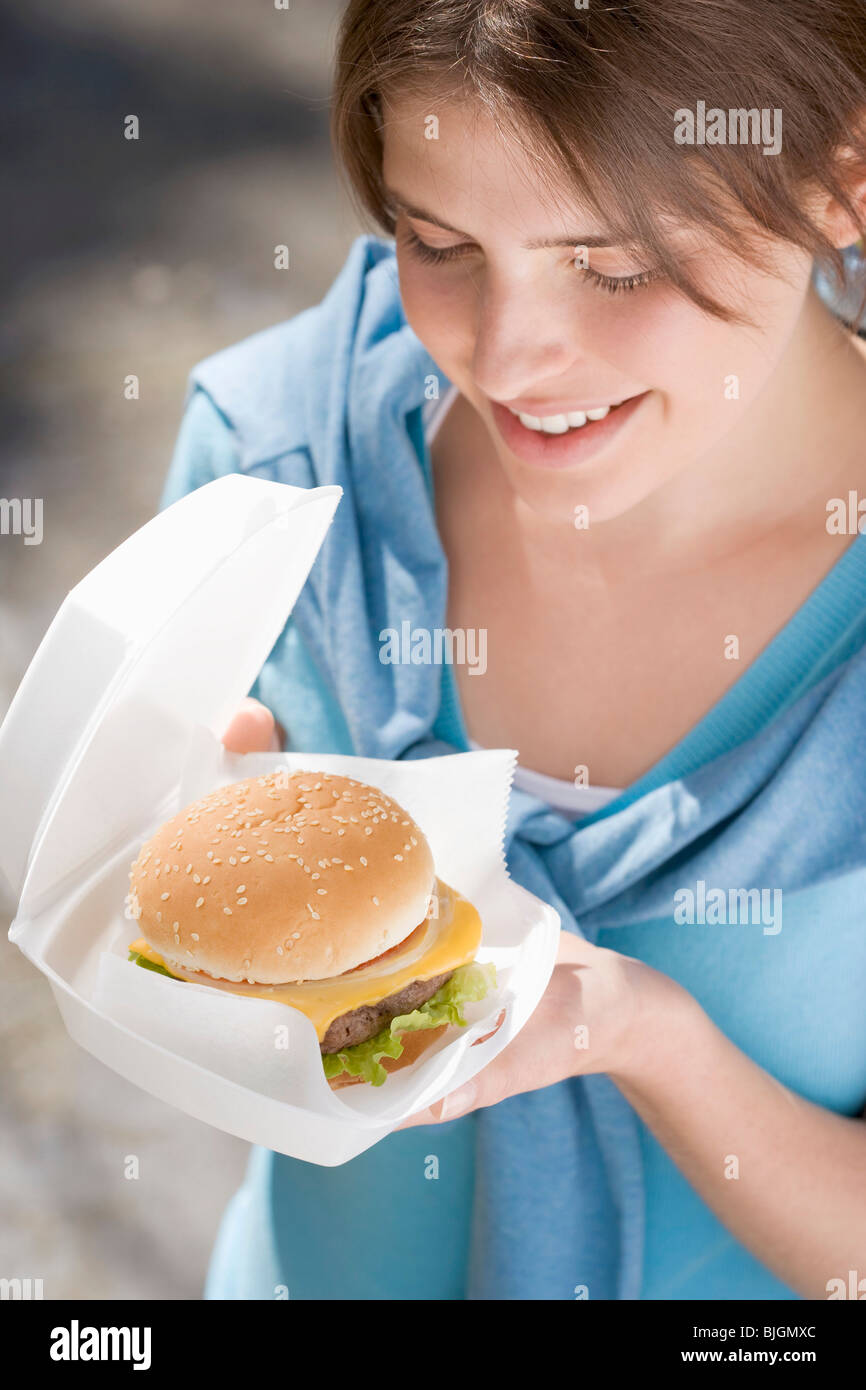 Jeune femme avec cheeseburger hors des portes - Banque D'Images