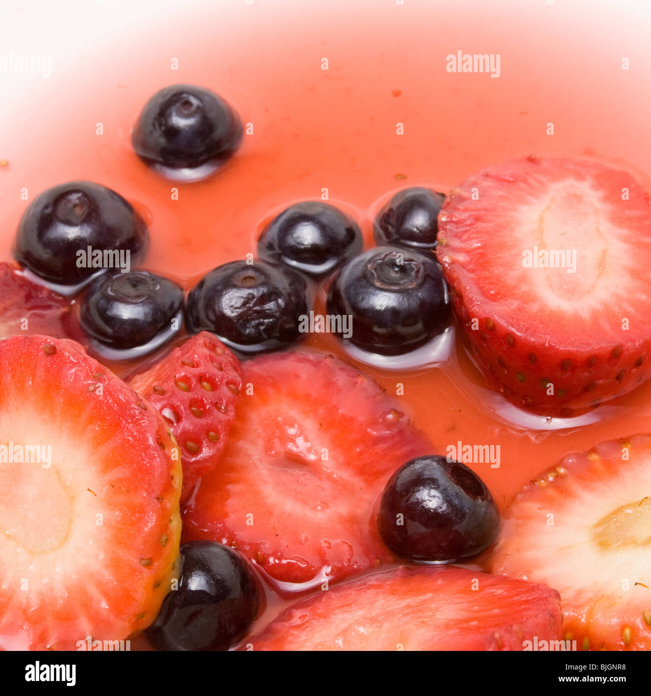 Les fraises tranchées et bleuets entiers au sirop d'arrière-plan de l'alimentation. Banque D'Images