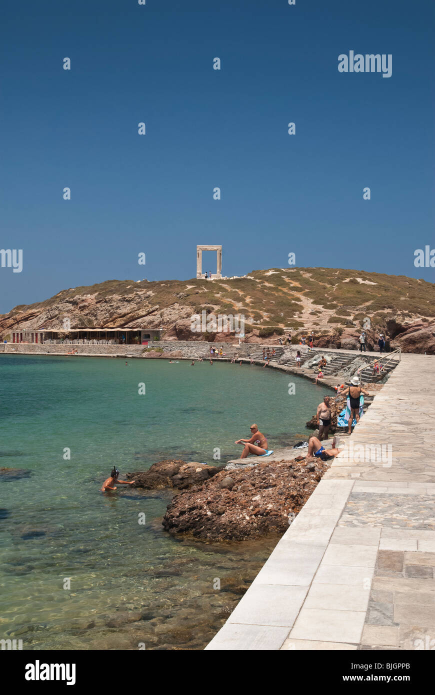 Les gens dans la mer le long de la chaussée menant au temple d'Apollon sur l'îlot de Palatia, Naxos, Grèce Banque D'Images