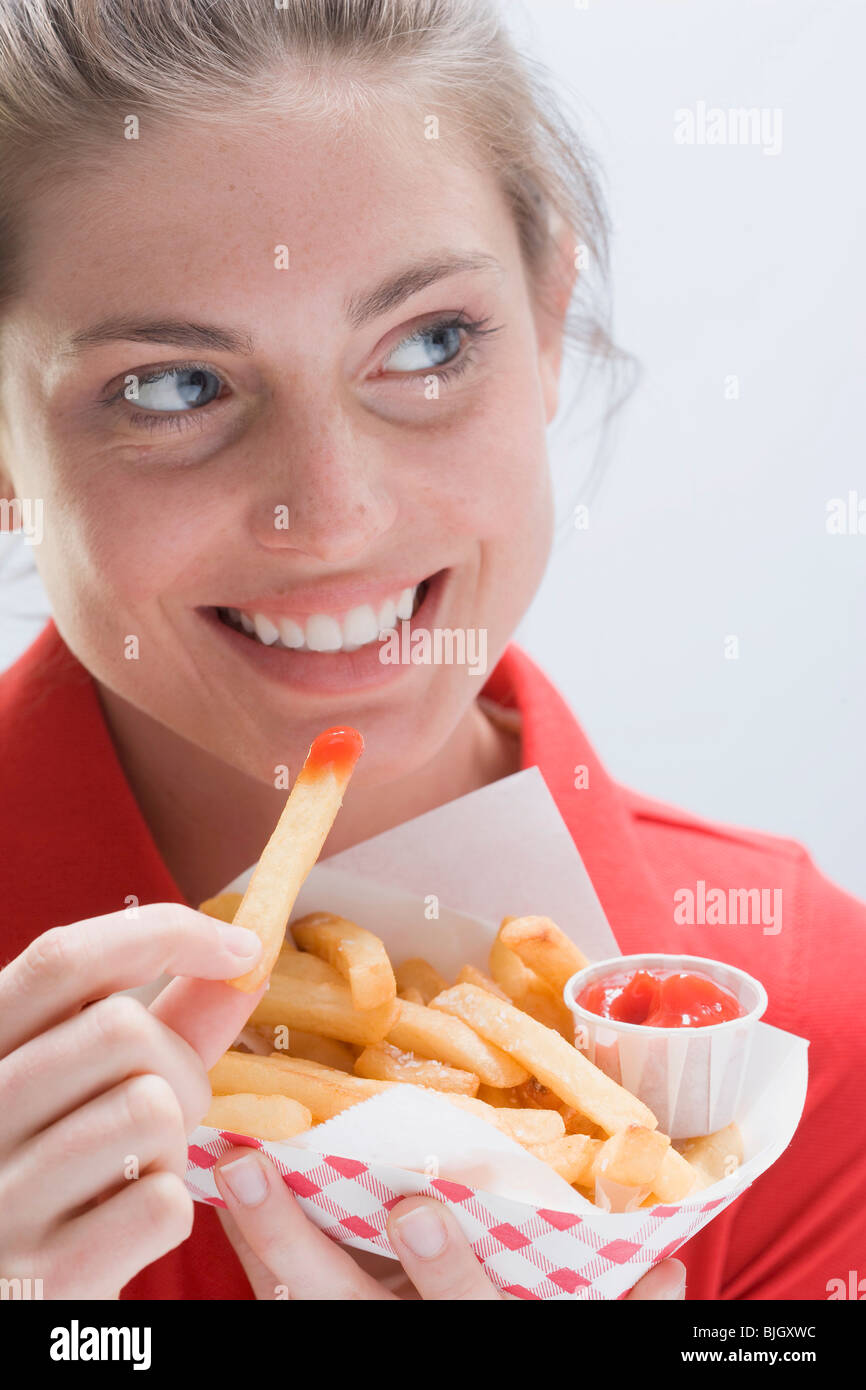 Smiling woman eating un sac de chips - Banque D'Images