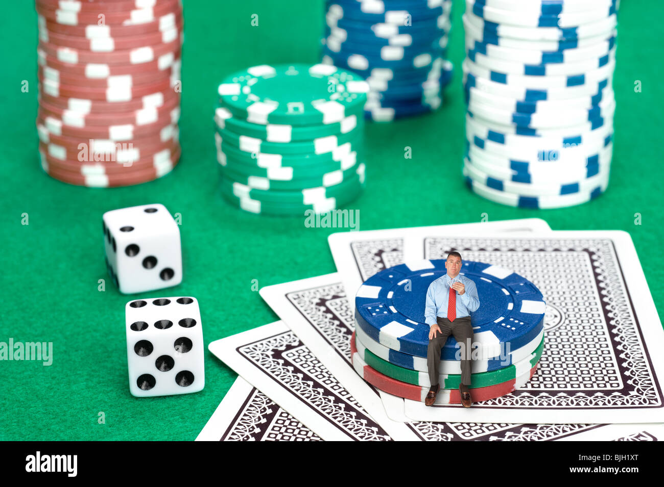 Un homme est assis sur une pile de jetons de poker dans une image conceptuelle du risque d'entreprise, chance et le désespoir. Banque D'Images