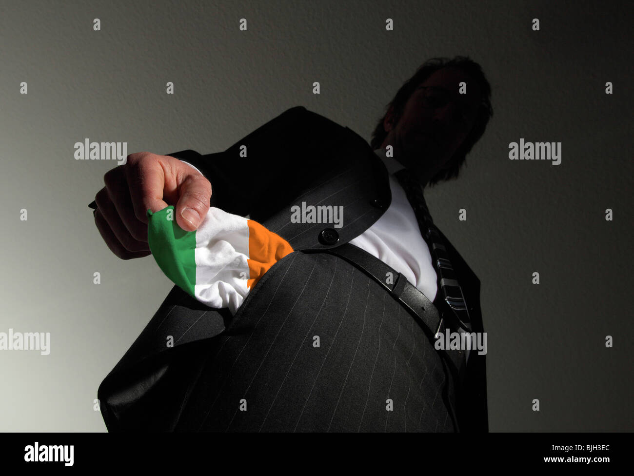 Homme en costume avec poches vides dans les couleurs nationales de l'Irlande. Symbole : L'Irlande est en faillite Banque D'Images