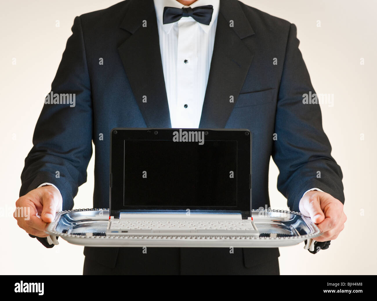 Butler holding laptop on tray Banque D'Images