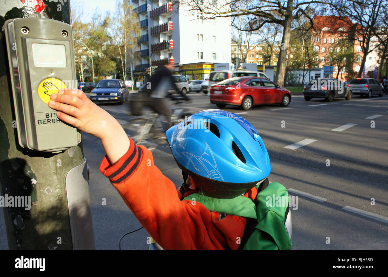 Un enfant appuie sur un bouton à un passage pour piétons Banque D'Images