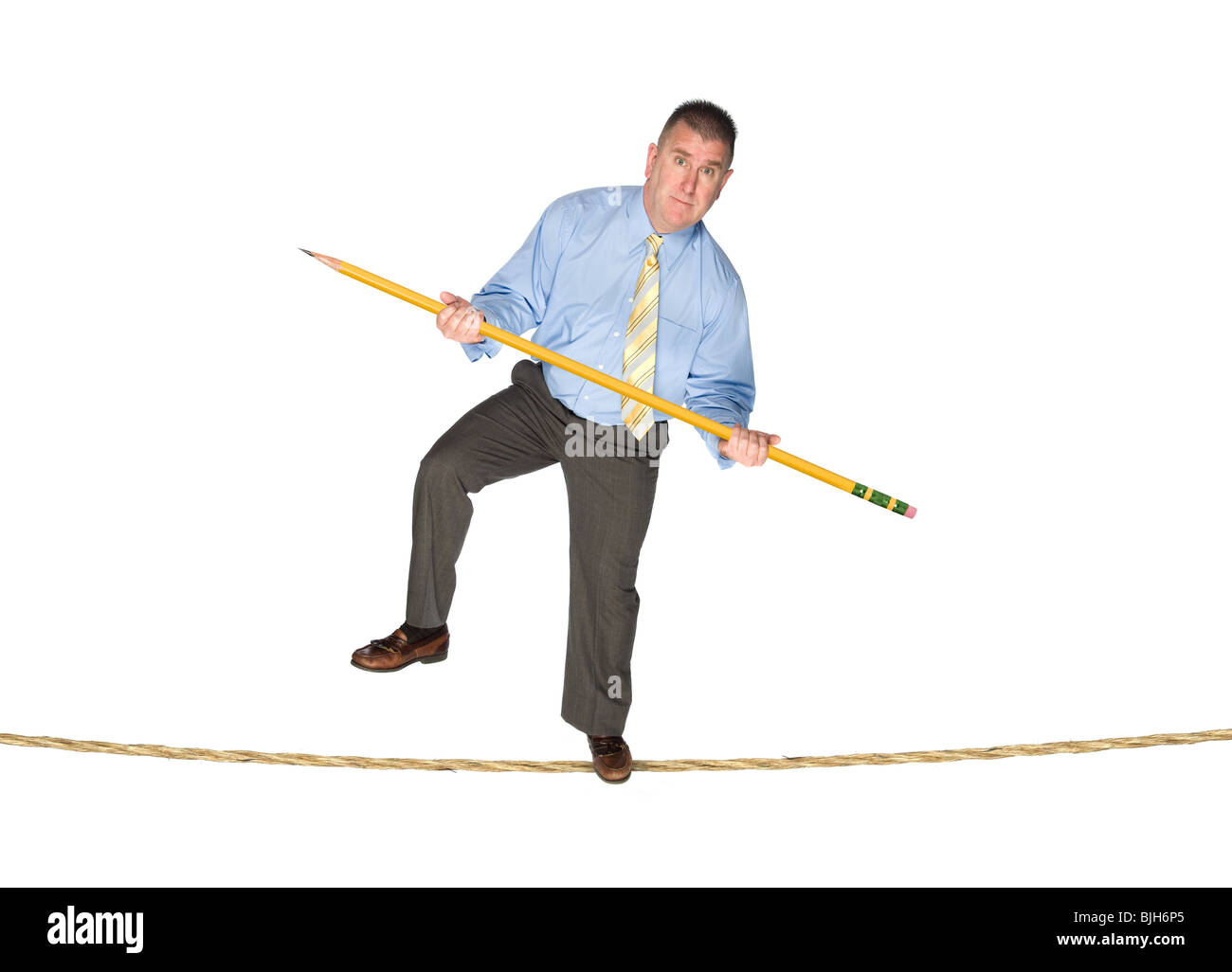 Un homme en équilibre sur un fil à l'aide d'un crayon géant comme un balancier. Banque D'Images