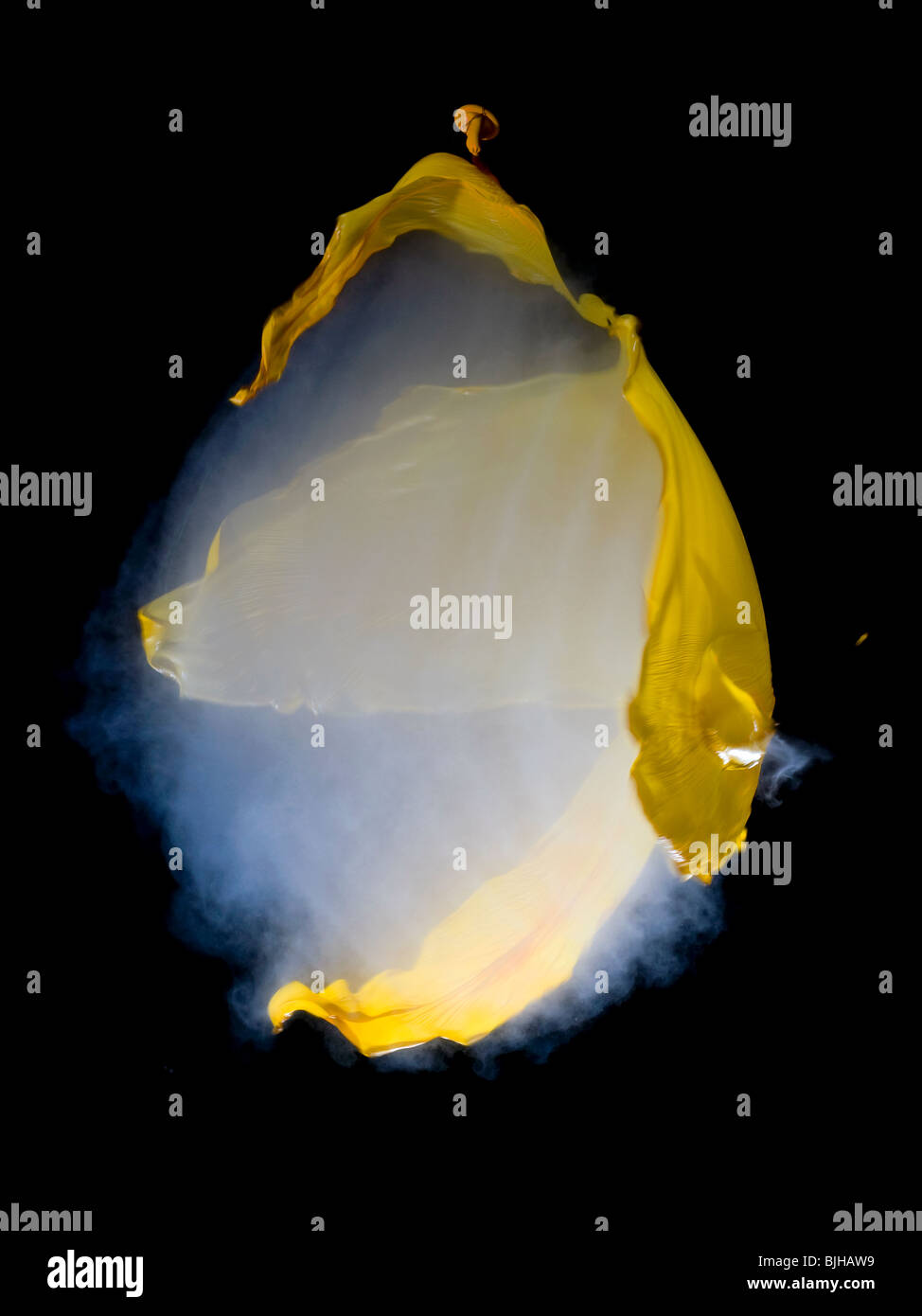 Un ballon jaune rempli de fumée lors de l'éclatement tourné avec une carabine à air. Visible de l'onde sonore Banque D'Images