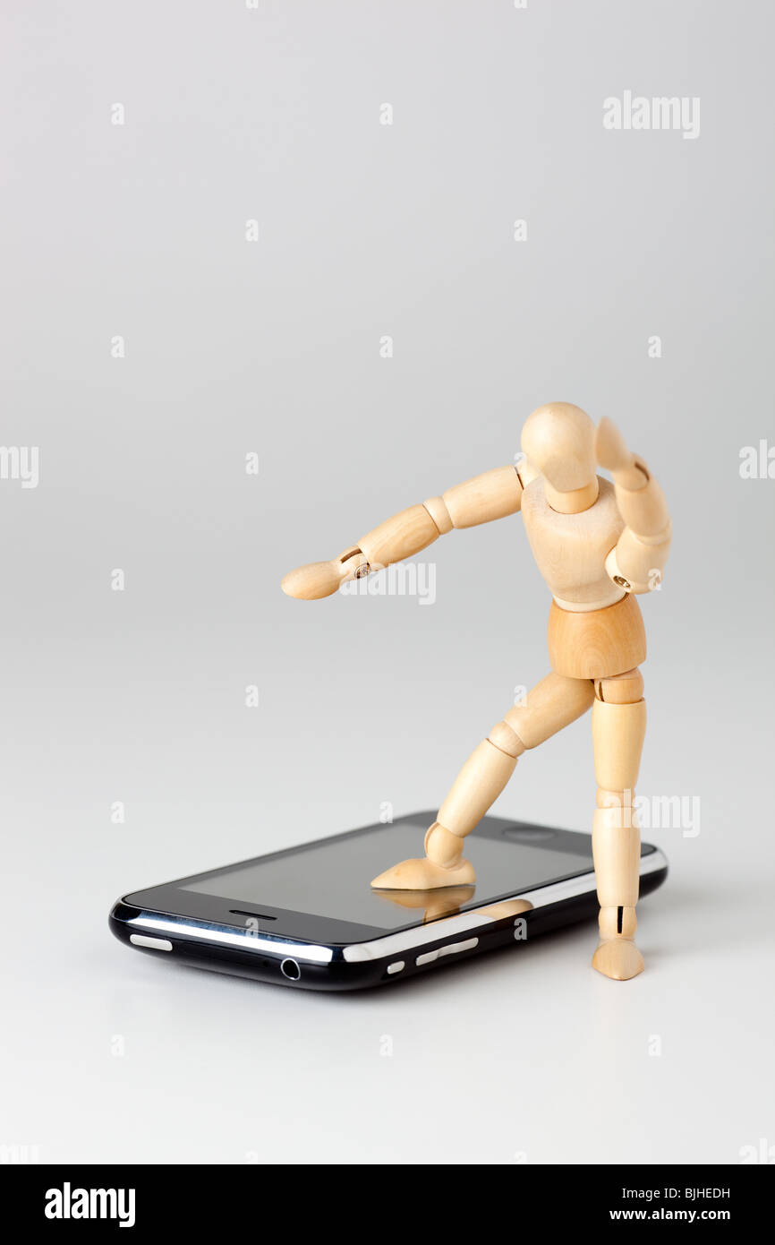 Mannequin jouet stepping on cell phone Banque D'Images