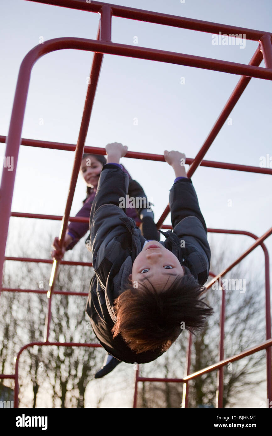 Garçon et fille en parc swinging sur bars s'amusant Banque D'Images