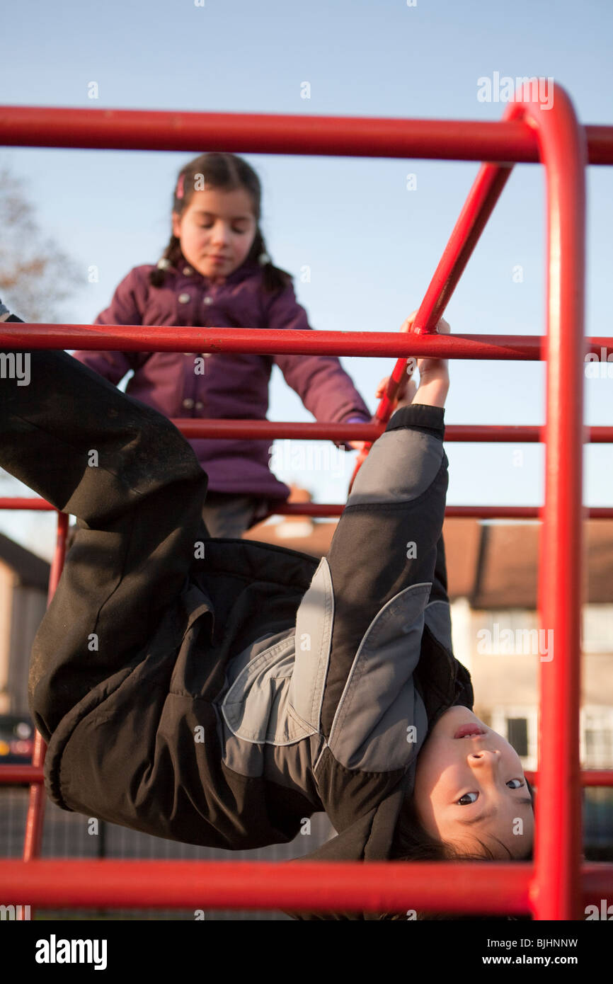 Garçon et fille en parc swinging sur bars s'amusant Banque D'Images