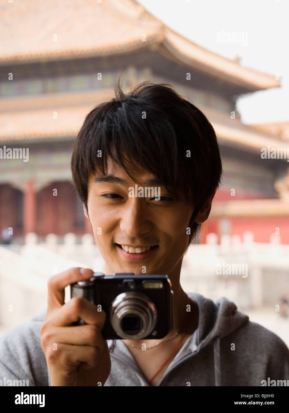Teenage boy outdoors smiling with digital camera Banque D'Images